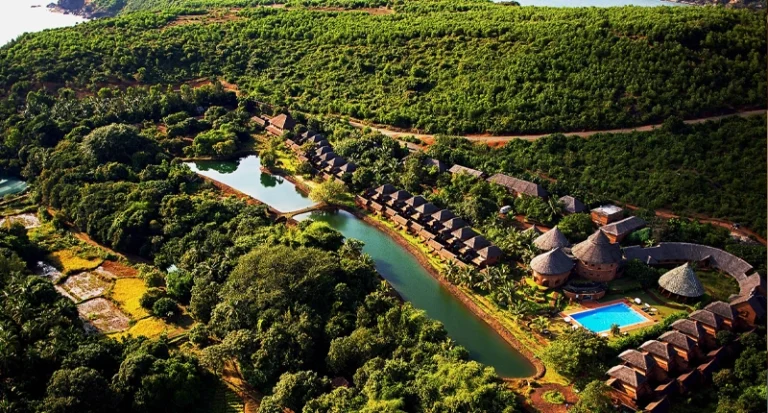 Aerial view of a luxury resort surrounded by lush green hills and a river