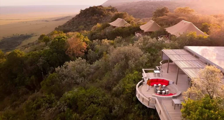 Aerial view of luxury safari tented lodge on a cliff overlooking vast savanna plains