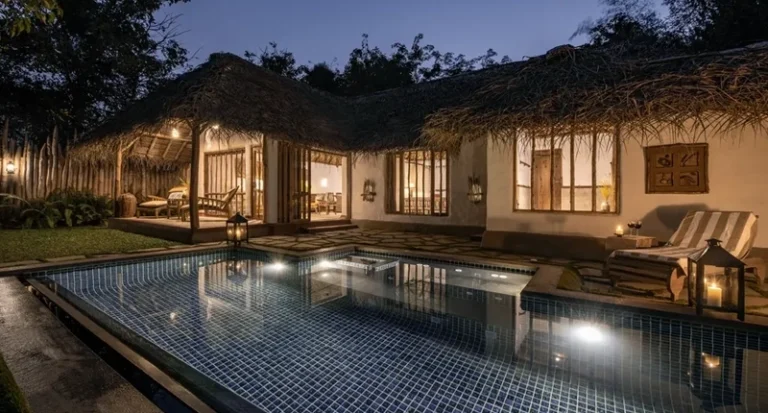 Luxury thatched cottage villa with private illuminated swimming pool at night