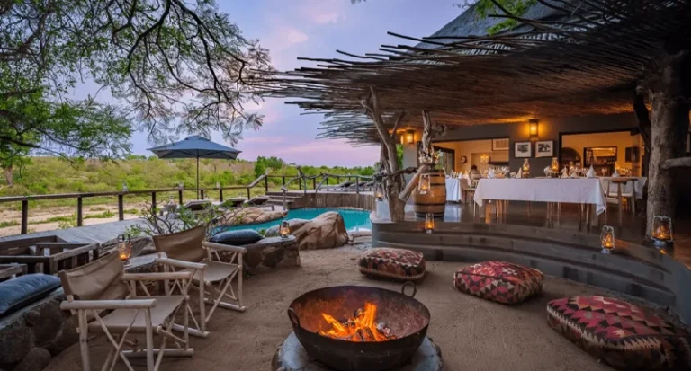 Luxury safari lodge patio with boma fire pit and outdoor dining area at dusk